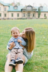 Fototapeta premium Mom and son are playing on the lawn. Mom and child are walking in the park. Relations between mom and son. Walk with the son.