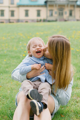 Mom and son are playing on the lawn. Mom and child are walking in the park. Relations between mom and son. Walk with the son.