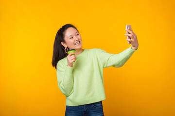 Cheerful young smiling woman is making a selfie while holding her to go cup