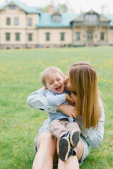 Mom and son are playing on the lawn. Mom and child are walking in the park. Relations between mom and son. Walk with the son.