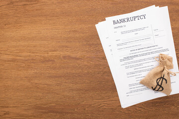 top view of bankruptcy papers and money bag on wooden background