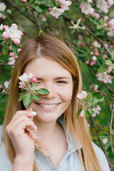 Girl in a flowering garden. A young blond woman is walking in a park. Portrait of a beautiful girl in the park.