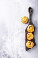 Food background with fresh pastry sweet swirl buns with raisins on wooden board for breakfast or brunch and coffee. Top view, copy space.