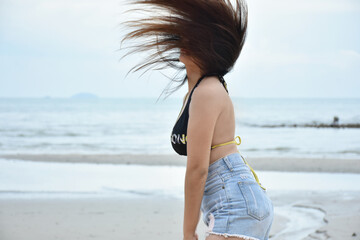Beautiful fashion asian women in swimwear posing action flick her hair between relaxation in weekend isolated with sea beach background.