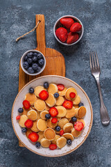 Tiny pancakes with strawberries and blueberries for breakfast.