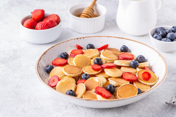 Tiny pancakes with strawberries and blueberries for breakfast.