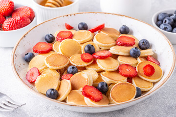 Tiny pancakes with strawberries and blueberries for breakfast.