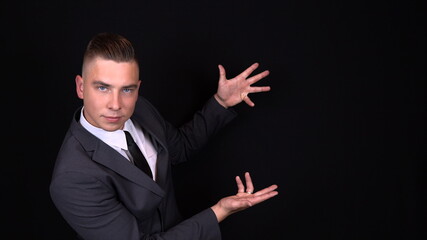 A young businessman points with their hands. Isolated black background