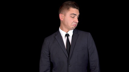 Young businessman straightens his suit. Man in a black suit on a black background
