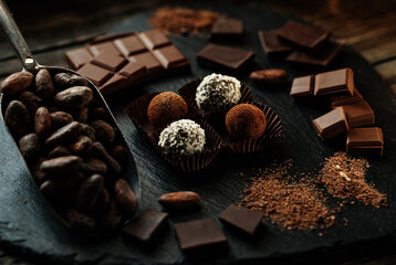 Handmade candies, two truffles with cocoa powder and two with coconut flakes. Chocolate candies inside of candy wrapper on blackstone stand