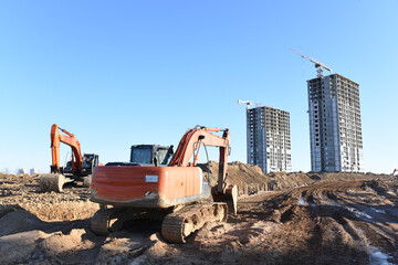 Excavator working at construction site on earthworks. Backhoe digging building foundation. Paving out sewer line. Heavy machinery for road work, excavating, loading, lifting and hauling of cargo