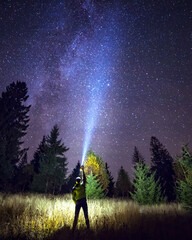 Naklejka na ściany i meble Silhouette of climber standing against the Milky Way with a flashlight in his hands. Location Carpathian, Ukraine, Europe. Astrophotography of milkyway. Dramatic scene. Discover the beauty of earth.