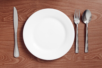 serving metal cutlery lie on a wooden table next to a plate