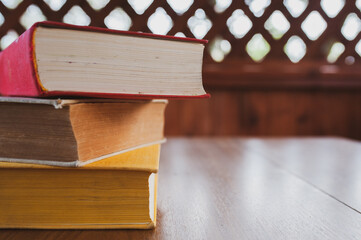 Stack of three books on a wooden table in the gazebo