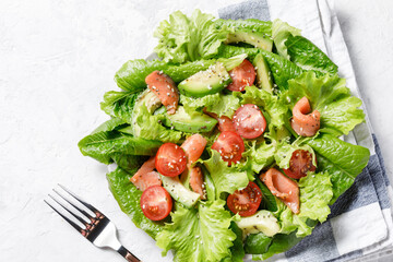 Salmon salad with avocado, green leaves, tomatoes on white background.