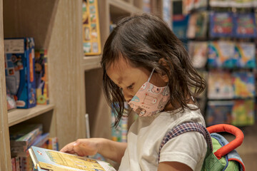 Adorable young Asian girl reading book 