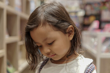 Adorable young Asian girl reading book 