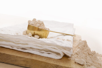 Wholegrain flour and scoop on wooden kitchen board.