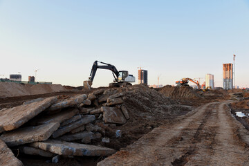 Fototapeta premium Excavator working at construction site on earthworks. Backhoe digging building foundation. Paving out sewer line. Heavy machinery for road work, excavating, loading, lifting and hauling of cargo