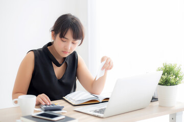 Beautiful young asian woman calculating expenses household and writing notebook on desk, girl checking bill and stress and note, female worry debt and tax, finance and business concept.