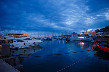 luxurious yachts and boats in the port at night. evening, pier, sea, and sky. 