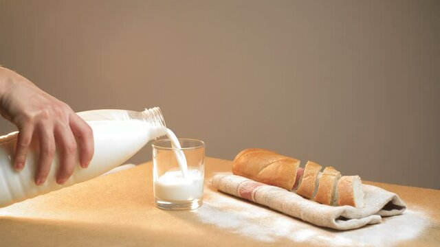 The woman's hand pours milk into a siper glass on the table. The concept of a quick breakfast