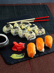 Set of sushi maki roll with sesame and soy sauce on a dark plate red background