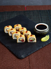 Set of sushi maki roll with sesame and soy sauce on a dark plate red background