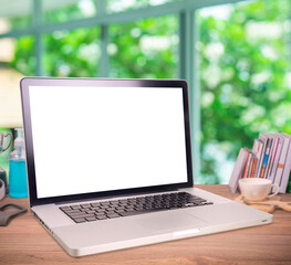 Laptop or notebook with blank screen on wood table in greenery blurry background