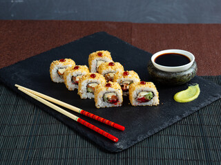 Set of sushi maki roll with sesame and soy sauce on a dark plate red background