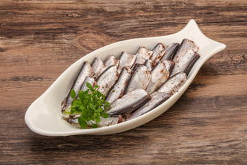 Anchovies in the bowl served basil leaves
