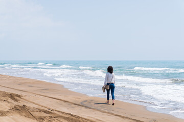 DELTA DE L'EBRE, TARRAGONA, CATALUNYA, SPAIN - JUNE 5, 2019: Beach of "punta de la banya" Young girl walking along the seashore.