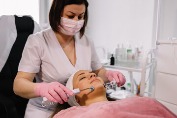 Beautiful smiling girl has a jet peel procedure in a cosmetology clinic. Health care, clinic, cosmetologists.