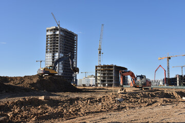 Excavators on earthworks. Backhoe on road work digs ground. Work of tower cranes at construction...