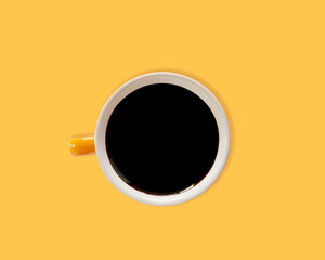 Black coffee in a bright orange cup, white inside on a flat lay and isolated yellow with clipping path Taken in the studio with copy space taken at an angle above