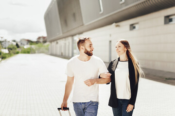 Close up portrait of happy young couple, man and woman go to the airport with a suitcase. Business trip or vacation trip. A sunny day for airplane flights