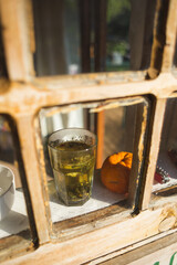 A glass with herbal tea stands on the windowsill of an old wooden house.