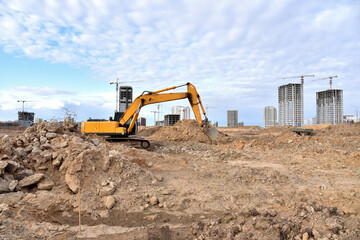 Obraz premium Excavator working at construction site on earthworks. Backhoe on road work digs ground. Paving out sewer line. Construction machinery for excavating foundation, loading, lifting and hauling of cargo