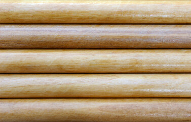 The texture of the surface of the log wall close up with round horizontal beams. The production and harvesting of forests. Background for the woodworking industry.