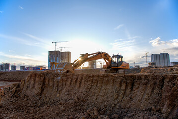 Excavator working at construction site on earthworks. Backhoe on road work digs ground. Paving out...