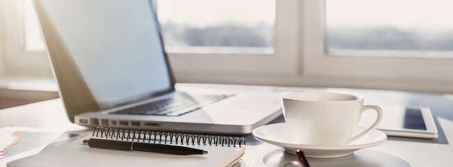 Workplace, laptop computer, coffee cup and notebook at office desk, panoramic banner. Business,...
