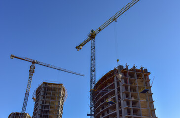 Tower crane lifting concrete bucket for pouring concrete during construction residential building on blue sky background. Builder workers during formwork and pouring concrete. New skyscraper