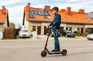 Young man riding on an electric scooter, housing estate