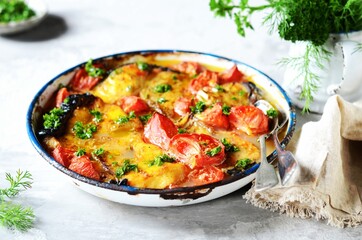 Baked fish (shark) with tomatoes and spices in a baking dish on a gray background, still life