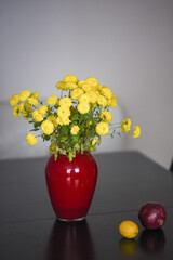 Red vase with a bouquet of yellow chrysanthemums
