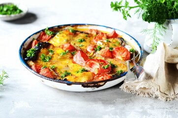 Baked fish (shark) with tomatoes and spices in a baking dish on a gray background, still life