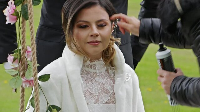 Close ups of busy professional photoshoot with the photographer, the groom and the beautiful bride who is sitting on a swing.
