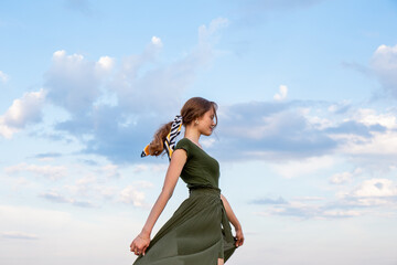 Young beautiful woman on a background of blue sky and clouds.