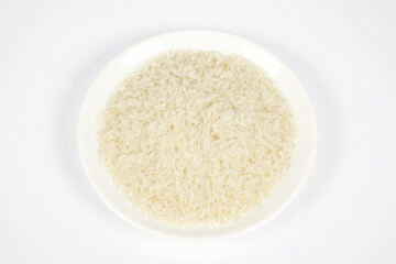 Plate of raw rice on white background. Top view.