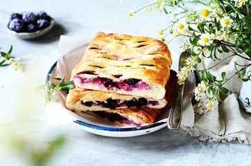 Homemade yeast cake with berries, blackberries, currants and blueberries in a plate on a gray background